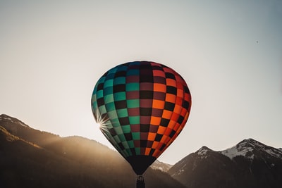白天在山附近飞行的红、黑、绿热气球
